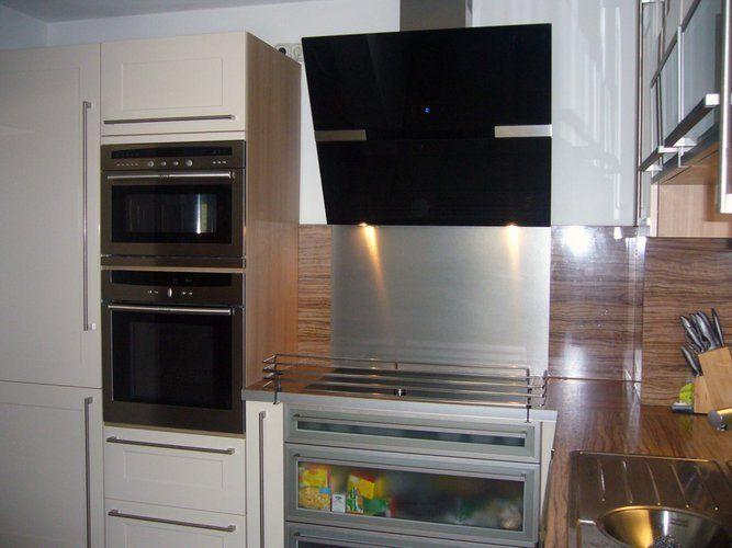 Unsere Referenzen — Detail Walnussküche mit Mikrowelle, Backofen und schwarzer Esse