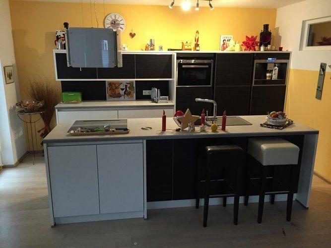 Unsere Referenzen — Showroom Wohnküche mit anthrazit Halbinsel, gelber Wand und Barhockern
