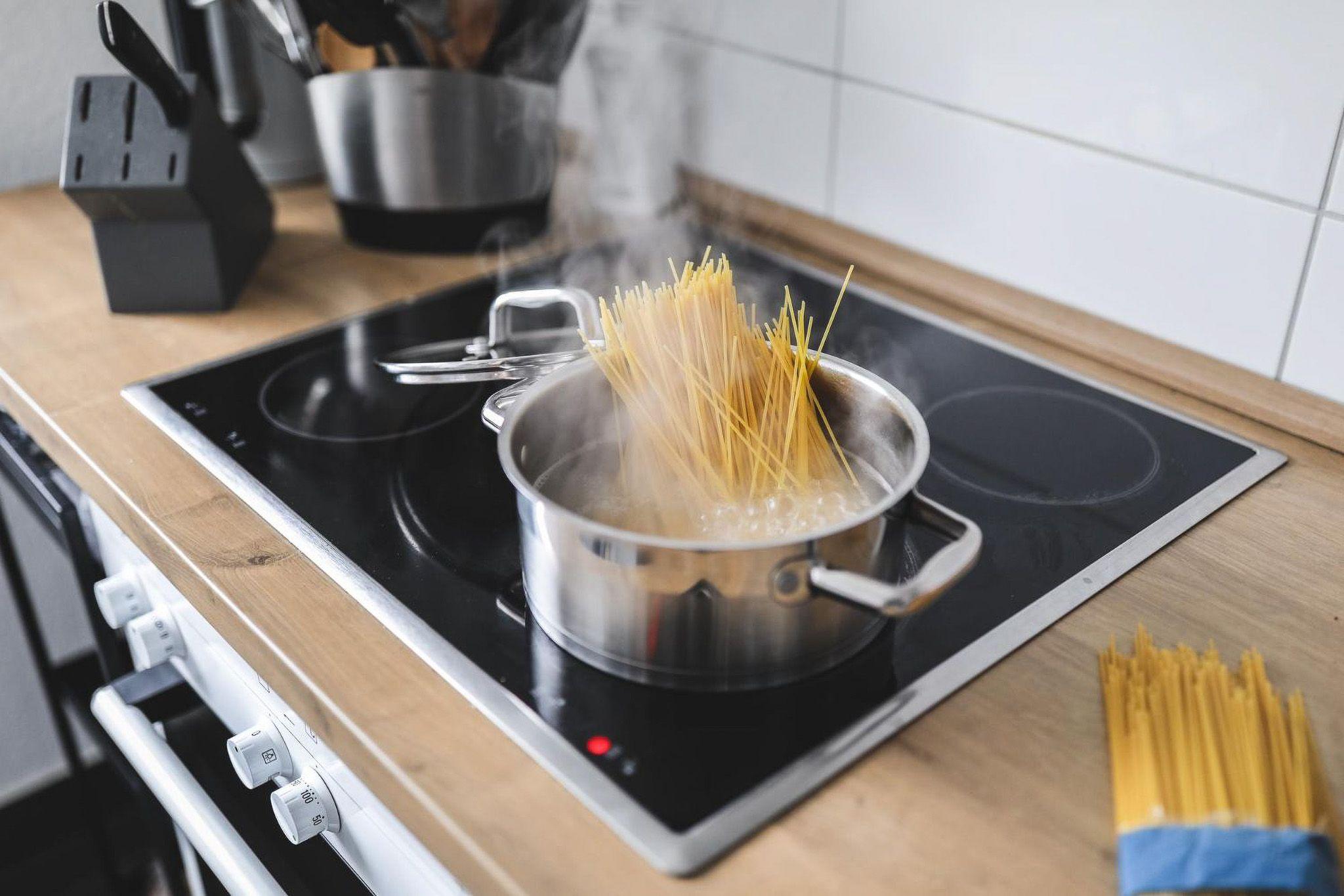 Cerankochfeld mit kochendem Topf und aufsteigendem Dampf von Spaghetti