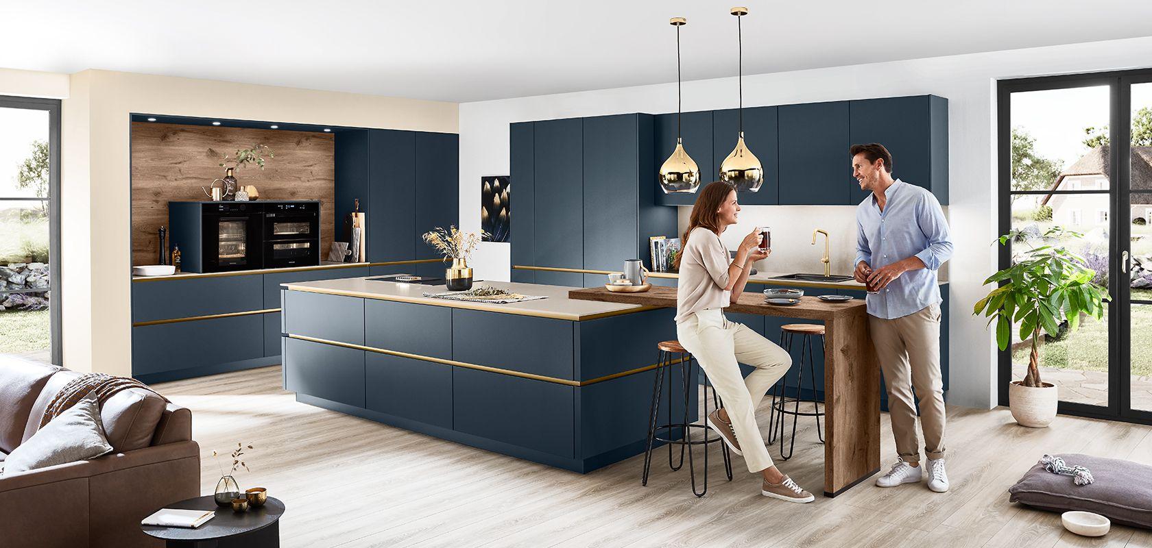Lassen Sie sich inspirieren — Blau-graue Kücheninsel mit goldenen Pendelleuchten und Paar mit Kaffee