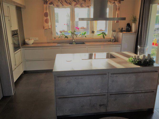 Unsere Referenzen — Weiße Küche mit Holz-Arbeitsplatte, Beton-Kochinsel und Edelstahl-Dunstabzug