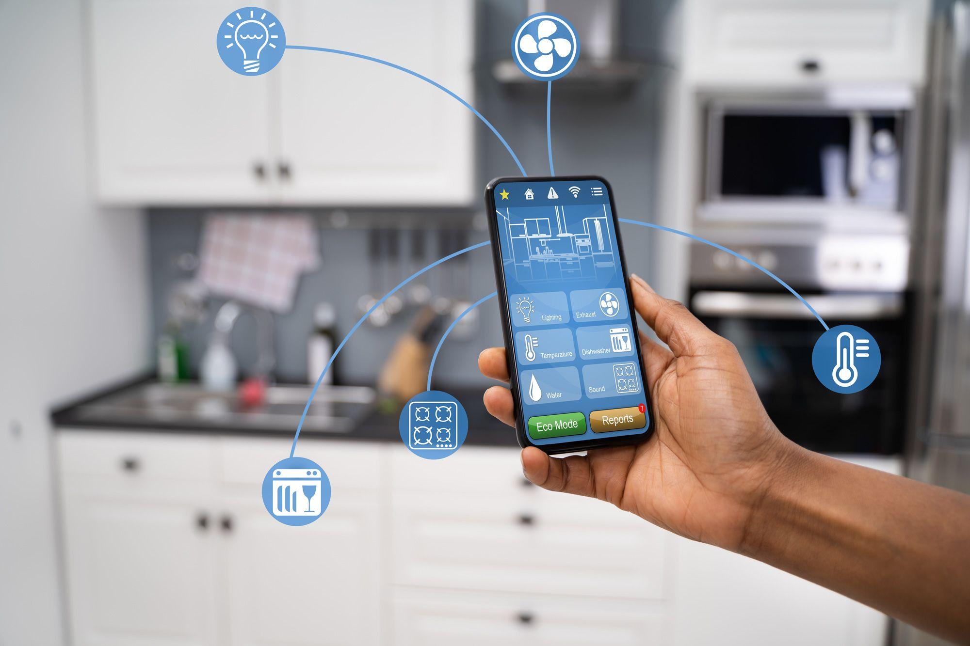 Smartphone mit Smart-Home-App und vernetzten Küchengeräte-Symbolen vor heller Küche