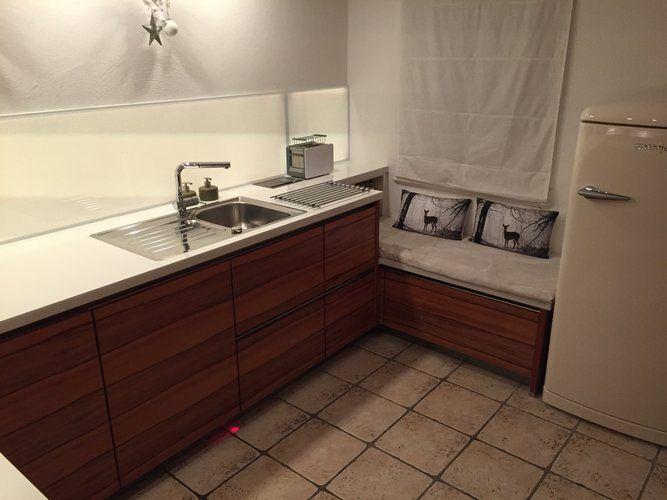 Unsere Referenzen — Walnuss-Küche mit Sitzecke, Hirschmotiv-Kissen und Smeg-Retro-Kühlschrank creme