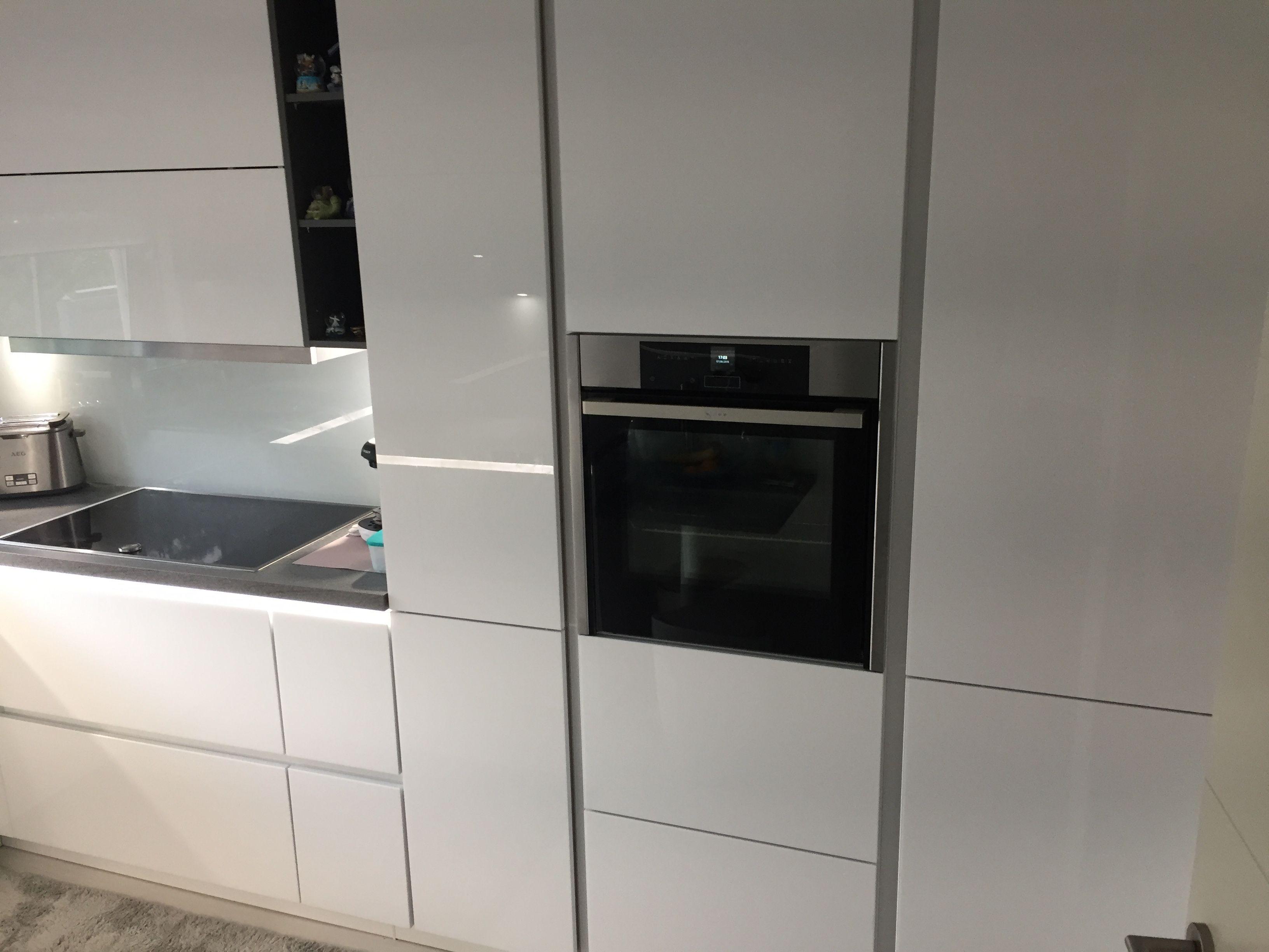 Unsere Referenzen — Weiße Hochglanzküche mit Backofen-Hochschrank und Glasvitrinen