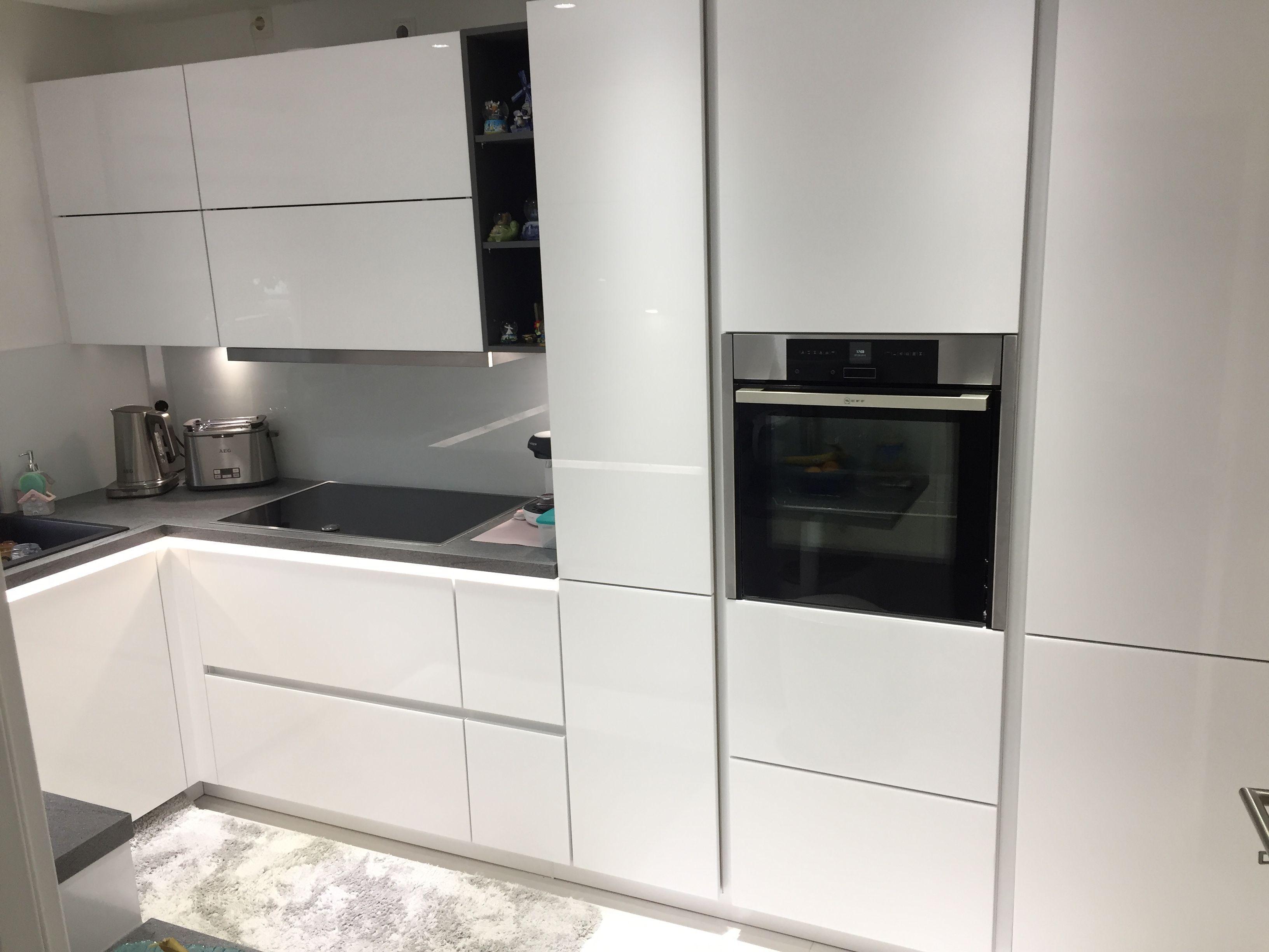 Unsere Referenzen — Weiße Hochglanzküche mit Eckspüle, Backofen und Bodenmatte