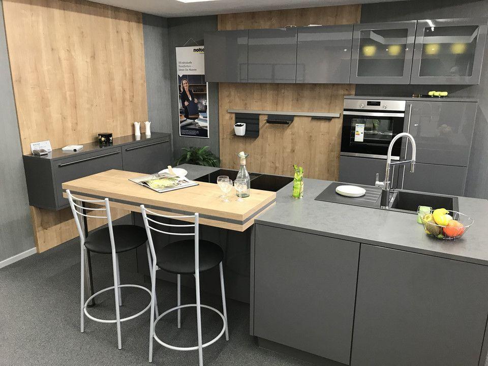 Unsere Ausstellung in Bischberg — Showroomküche mit grauen Hochglanzfronten, Holz-Akzent, Bar mit zwei Barhockern