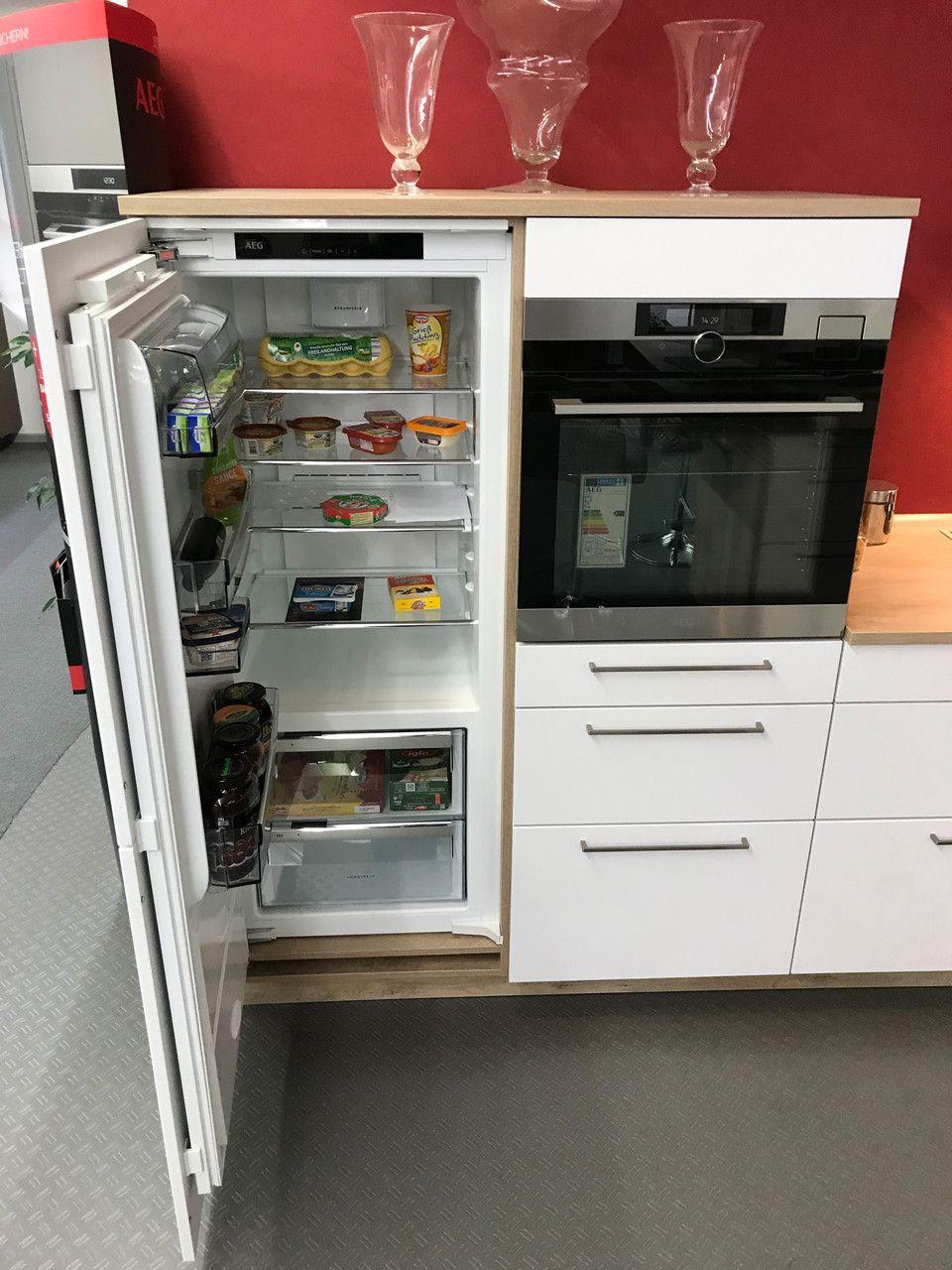 Unsere Ausstellung in Bischberg — Geöffneter AEG Einbau-Kühlschrank mit Lebensmitteln neben Einbaubackofen