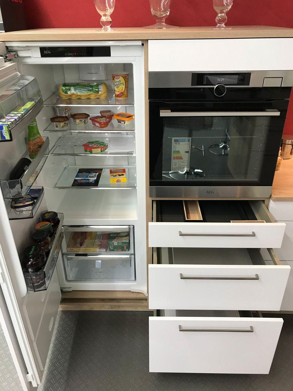 Unsere Ausstellung in Bischberg — Geöffneter AEG Kühlschrank neben Edelstahl-Backofen mit Werbeaufkleber