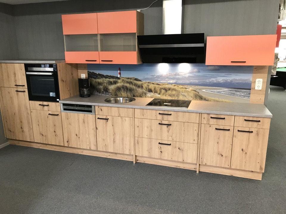 Unsere Ausstellung in Bischberg — Showroomküche mit Eiche-Optik-Fronten, lachsfarbenen Akzenten und Strandbild-Spritzschutz