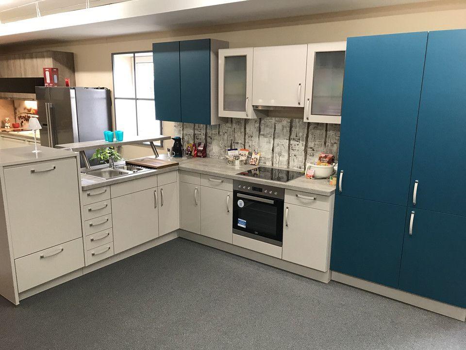 Unsere Ausstellung in Bischberg — Showroomküche mit petrolblauen Hochschränken, Beton-Spritzschutz und Edelstahl-Kühlschrank