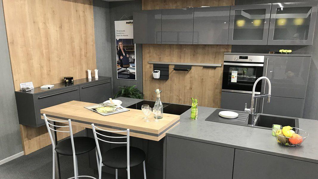 Showroom-Küche in Anthrazit-Hochglanz mit Holzdekor-Theke und Aufsteller im Hintergrund